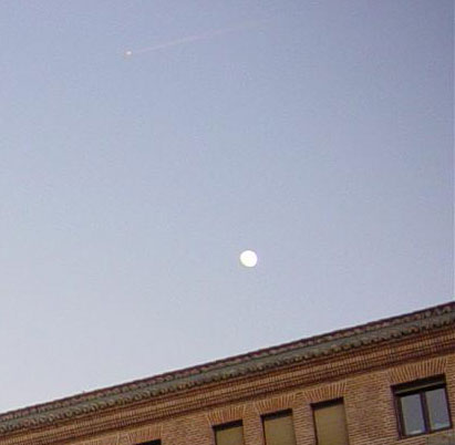 Point lumineux avec traînée au-dessus de la lune